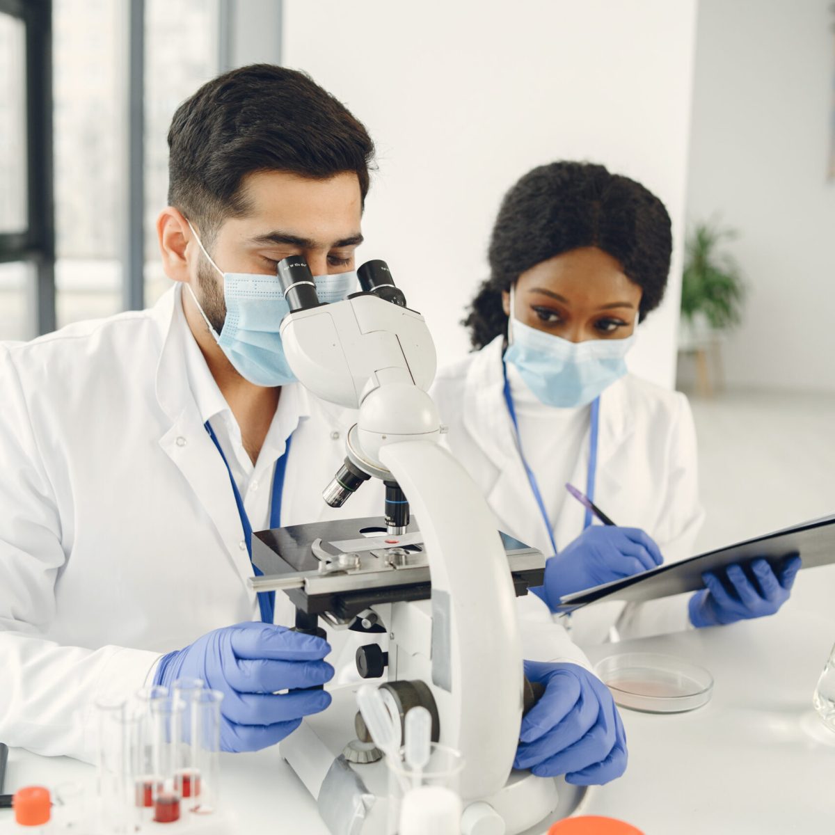 New test. Concentrated skilled researchers wearing uniform. Doing test, creating vaccine.